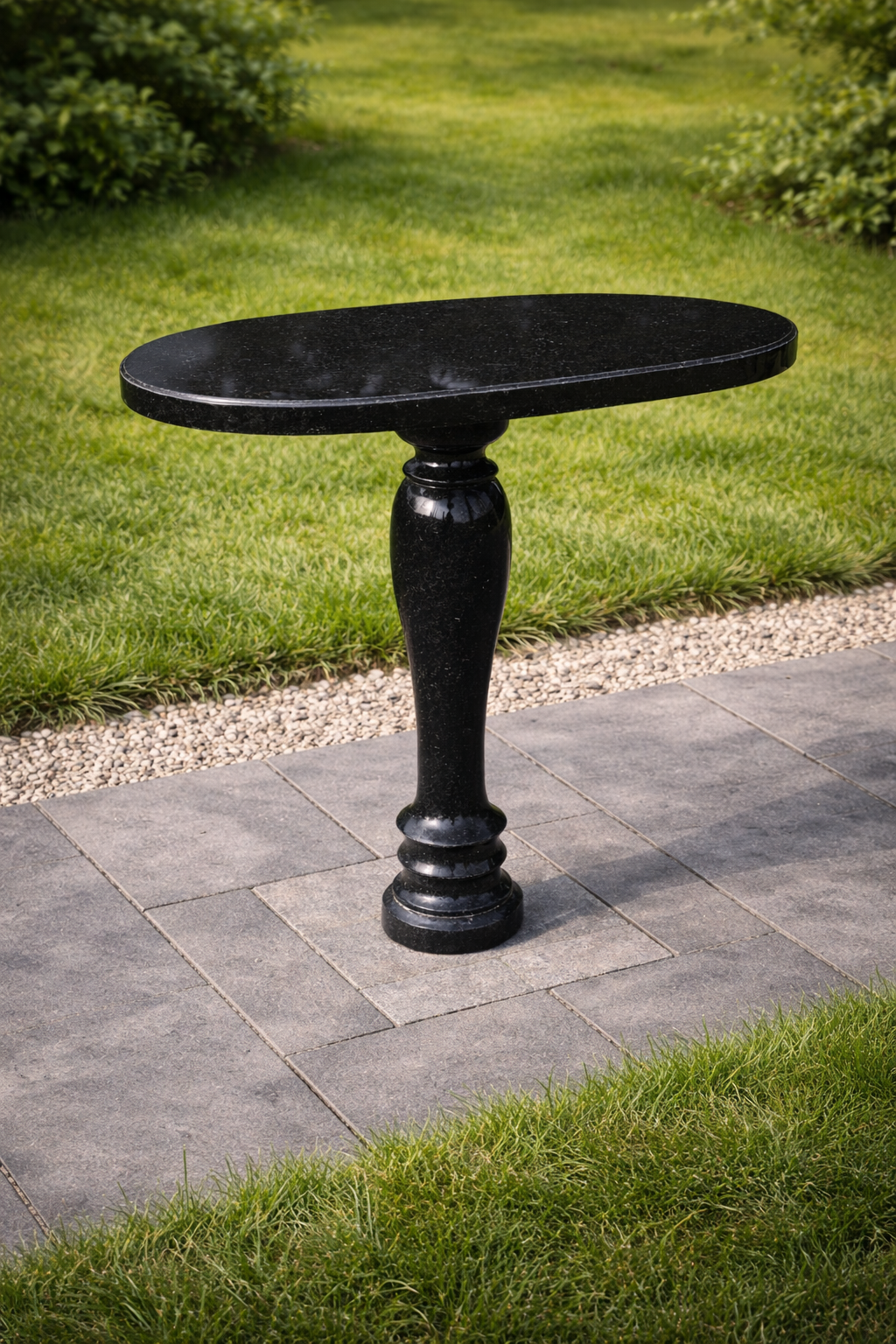 granitnyy-ovalnyy-stol-85-sm-iz-chernogo-gabbro-buki Гранитный овальный стол 85 см из чёрного габбро-диабаза для благоустройства могилы, установленный на плитке с травой на фоне