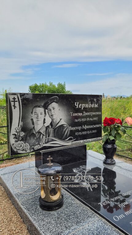 Семейный горизонтальный памятник из черного гранита с двумя портретами и художественным оформлением